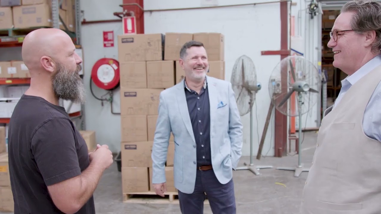 three men standing in front of a stack of boxes talking