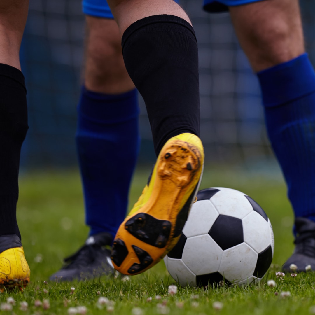 yellow soccer boot and a soccer ball