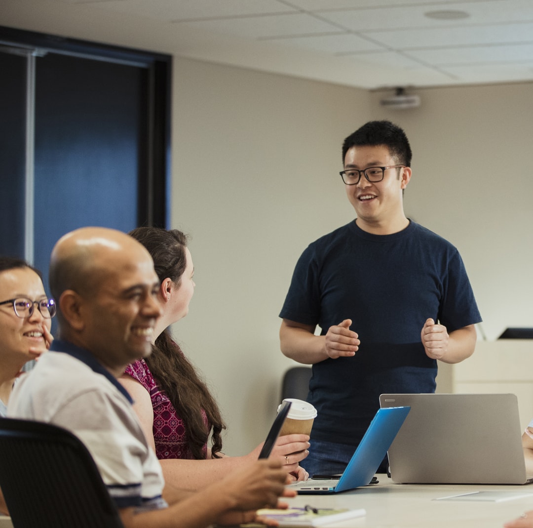 man standing up and making colleagues laugh