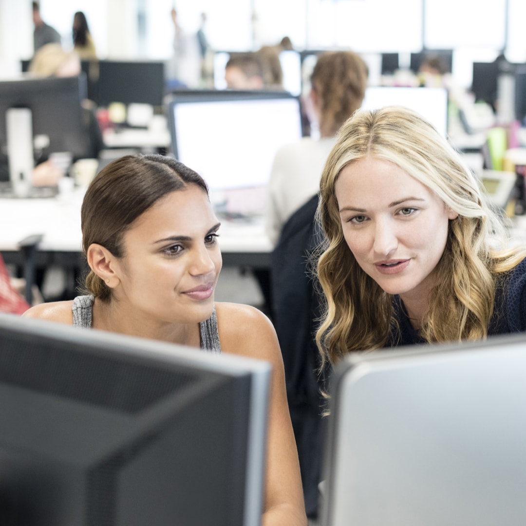 two female office workers looking at computer screens